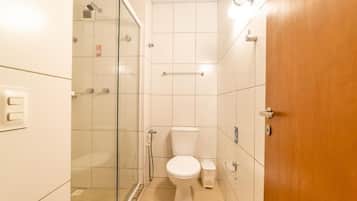 Un baño con cabina de ducha de vidrio, inodoro y puerta de madera.