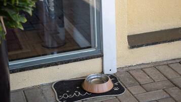 Ein Hotel Eingang mit einem 'DOG BAR' Schild, einem Topf mit Pflanze und einer Hundeschüssel auf dem Boden.