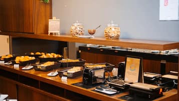 Un mostrador de buffet con distintos alimentos y una máquina de café.