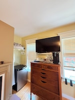 Una cocina compacta con refrigerador, un mueble de madera con televisión de pantalla plana y una ventana con persianas.