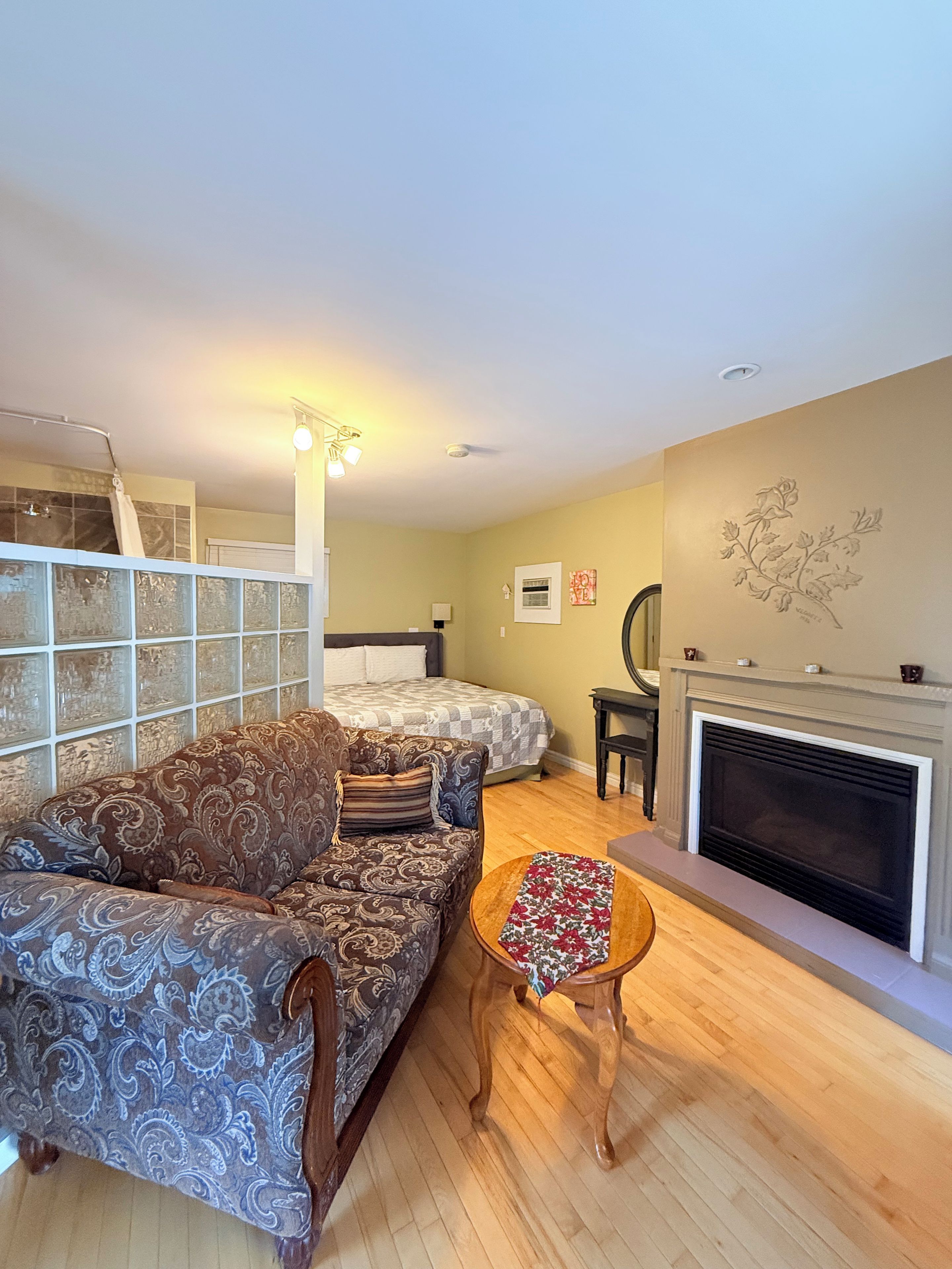 A room with a sofa, a small table, a fireplace, and a bed.