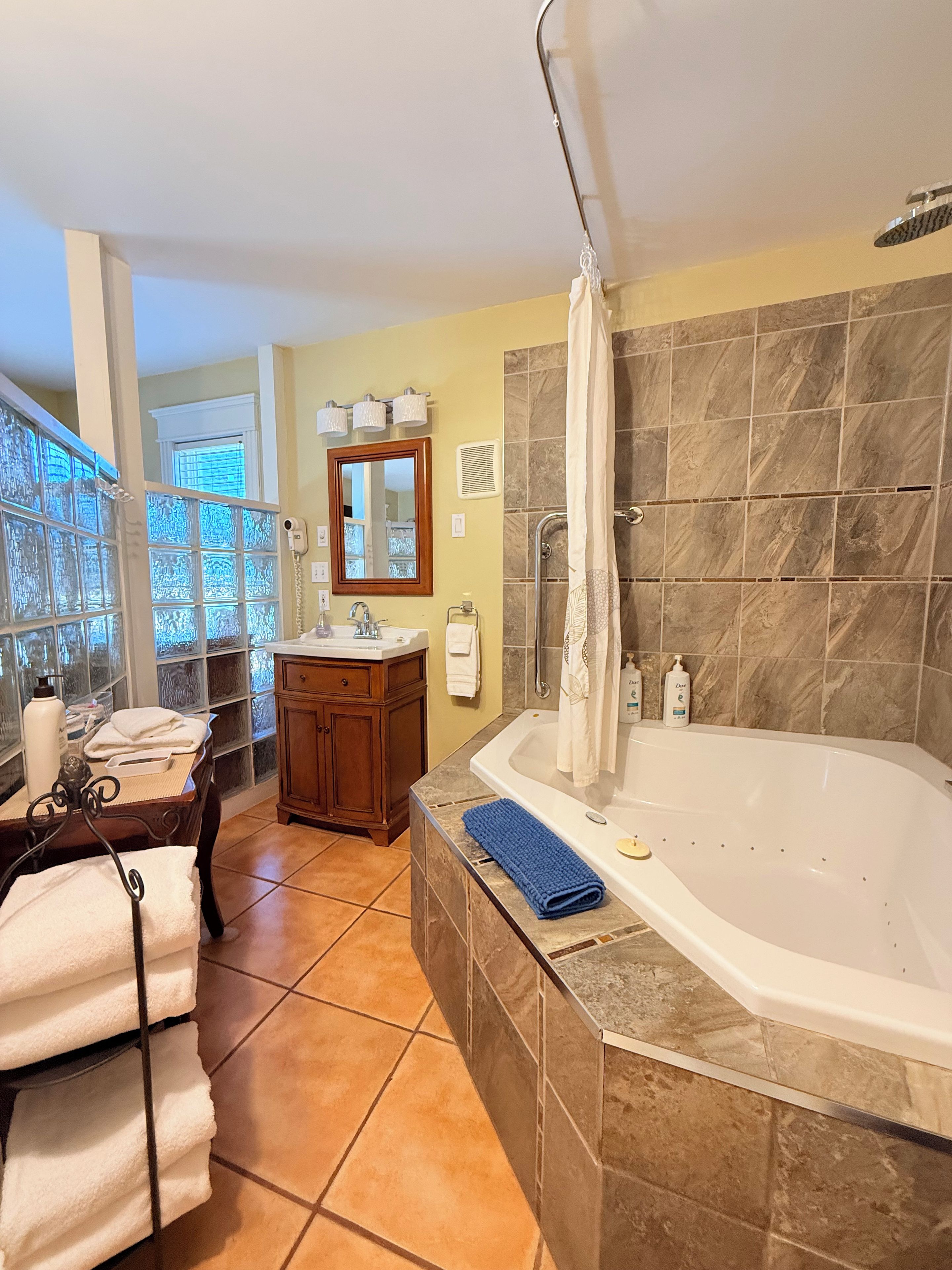 Une salle de bain avec une baignoire, un meuble-lavabo, une fenêtre et un rideau de douche.