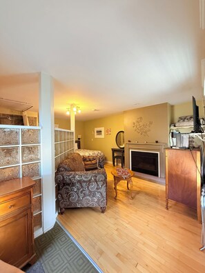 A living room with a fireplace, a sofa, a coffee table, and a television. - Heartwood Inn (Drumheller)