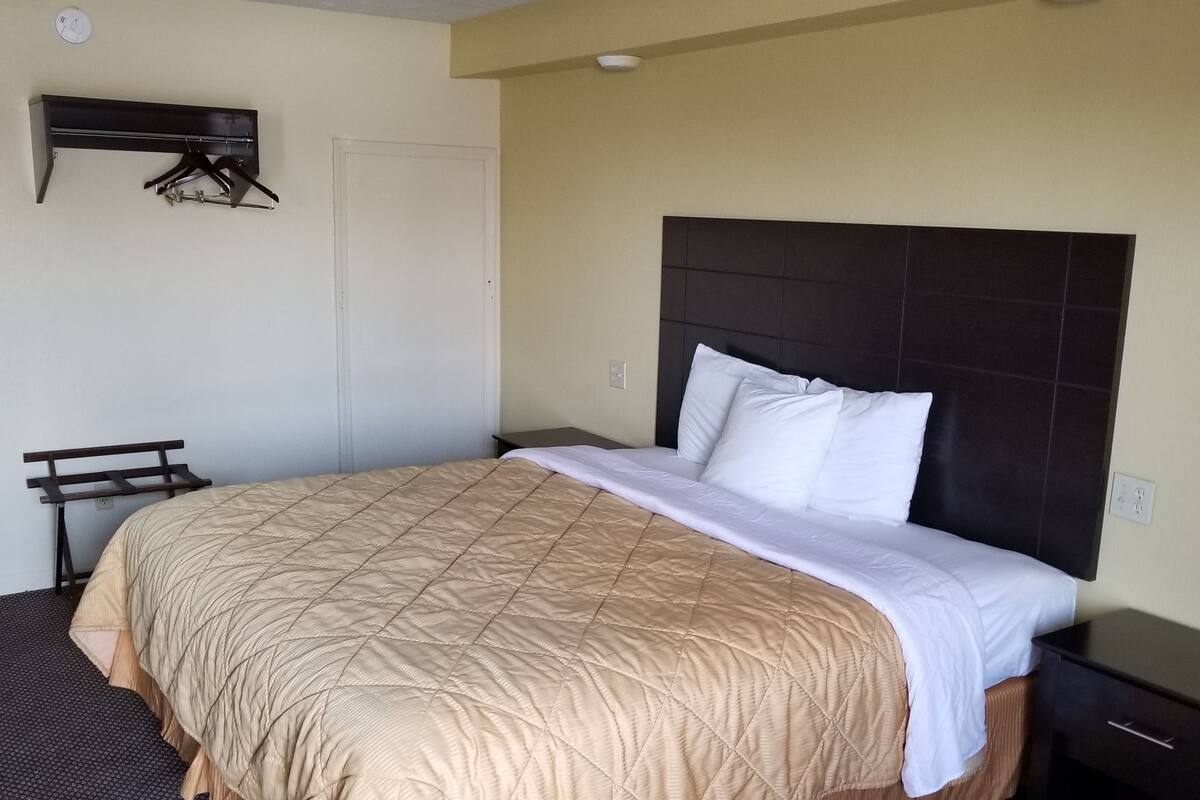 A hotel room with a bed, a nightstand, a wardrobe, and a coat rack.
