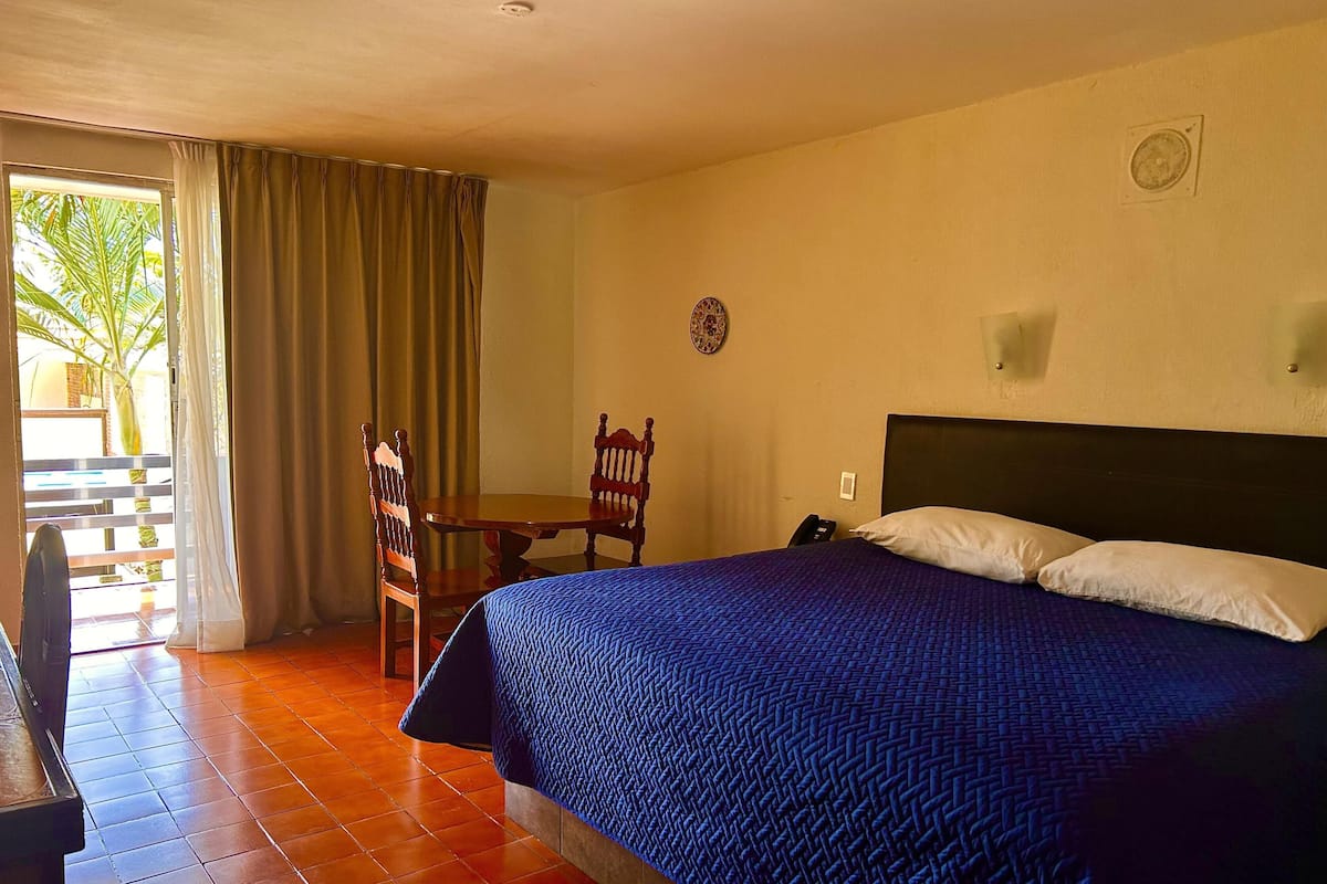 Una habitación de hotel con cama, una silla, una mesa y vistas al exterior.