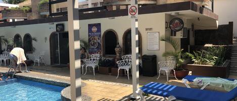 A pool area with lounge chairs, a covered seating area, and a sign indicating no food or drink allowed.