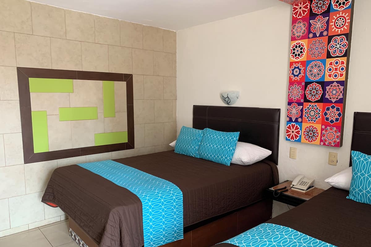 Habitación de hotel con dos camas, un adorno de pared con diseño y un teléfono en la mesita de noche.
