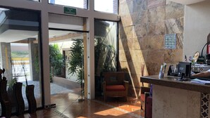 Un vestíbulo de hotel con una recepción, una silla y un letrero que indica una salida de emergencia.