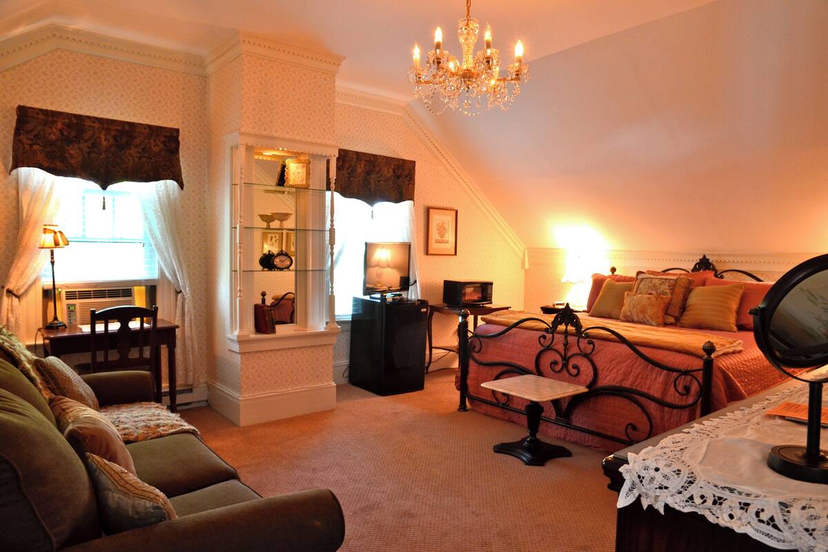 A cozy room with a bed, a desk, a chair, and a table.