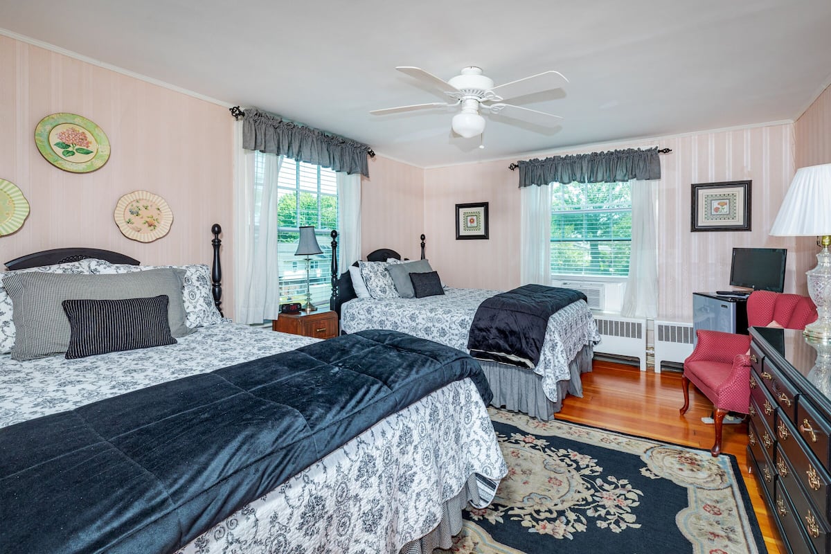 A bedroom with two beds, a ceiling fan, and a dresser.