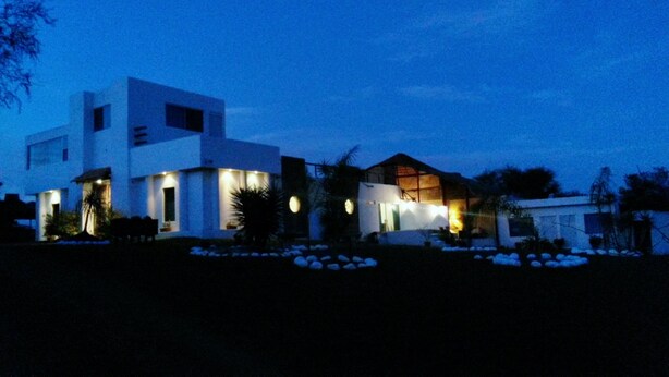 A modern two-story house with multiple illuminated windows and a well-maintained garden. - Nativa Posada & Spa (Montemorelos)