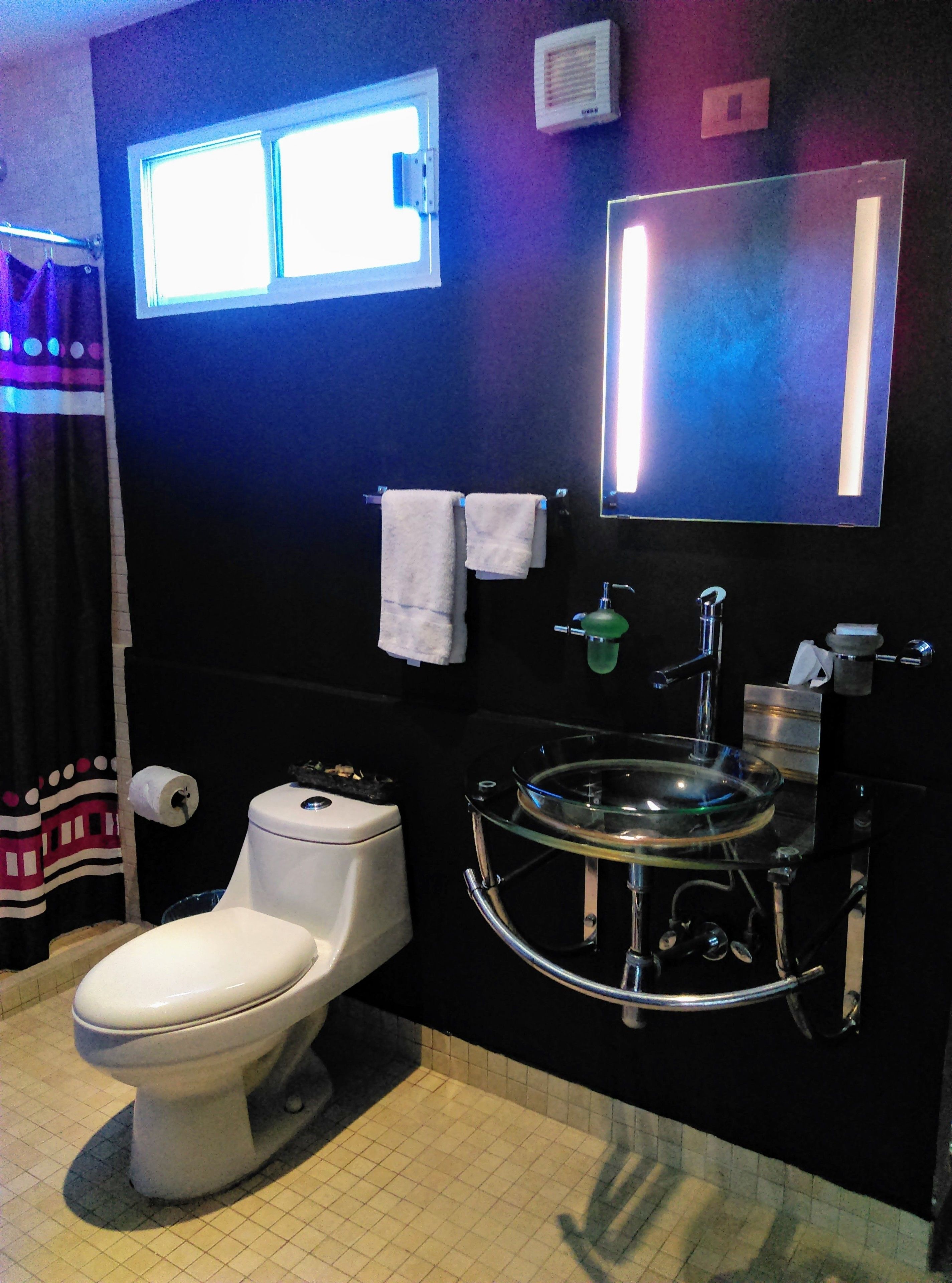 A bathroom with a toilet, a sink, a mirror, and a window.