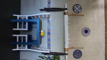 Un comedor con una mesa azul y sillas blancas, un pequeño arreglo floral y platos decorativos en la pared.