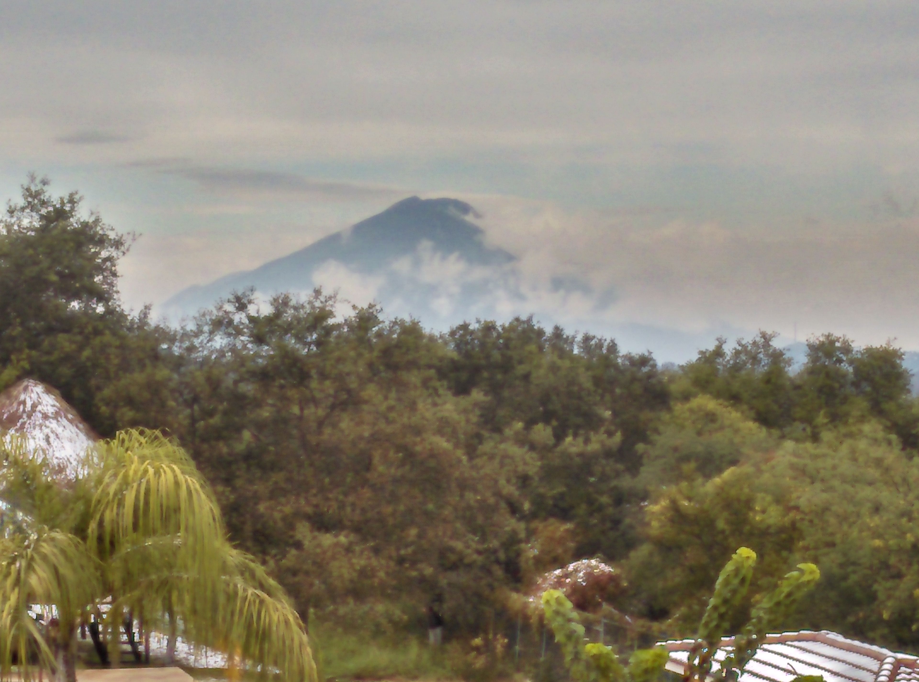 Ein Berg mit einem Gebäude mit Strohdach im Vordergrund.
