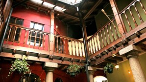 A multi-level wooden staircase with a red wall and hanging plants.