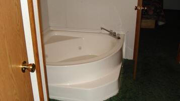 A bathtub in a bathroom with a wooden door and a towel rack above it.