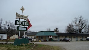 Un motel llamado Comfort Green, con techo verde y un letrero en forma de estrella.
