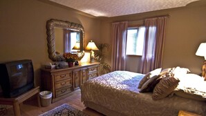 A bedroom with a large bed, a dresser, a television, and a mirror. - McDougall Lane Bed & Breakfast (Drumheller)