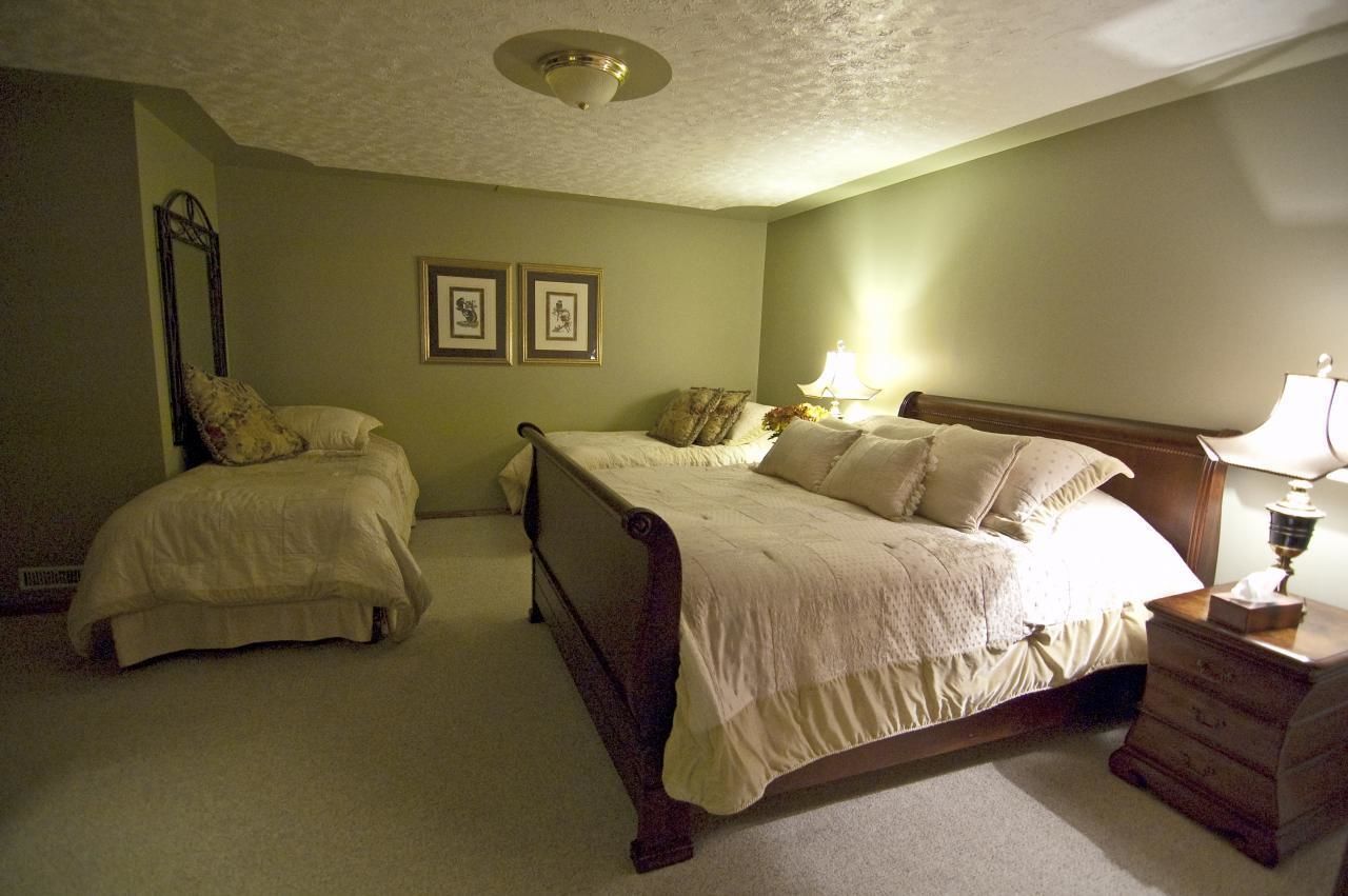 Une chambre avec deux lits simples, une table de chevet, une commode et un luminaire au plafond.