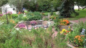 A garden with a circular seating area, surrounded by various plants and flowers.