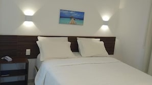 A neatly made bed with white linens, a wooden headboard, and two wall-mounted lights. - Pousada Galemares (Maragogi)