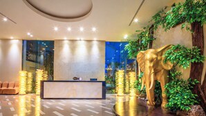 Ein Empfangsbereich mit einer Marmor-Theke, einer großen, goldenen Elefantenskulptur und einer Wand mit Pflanzen.