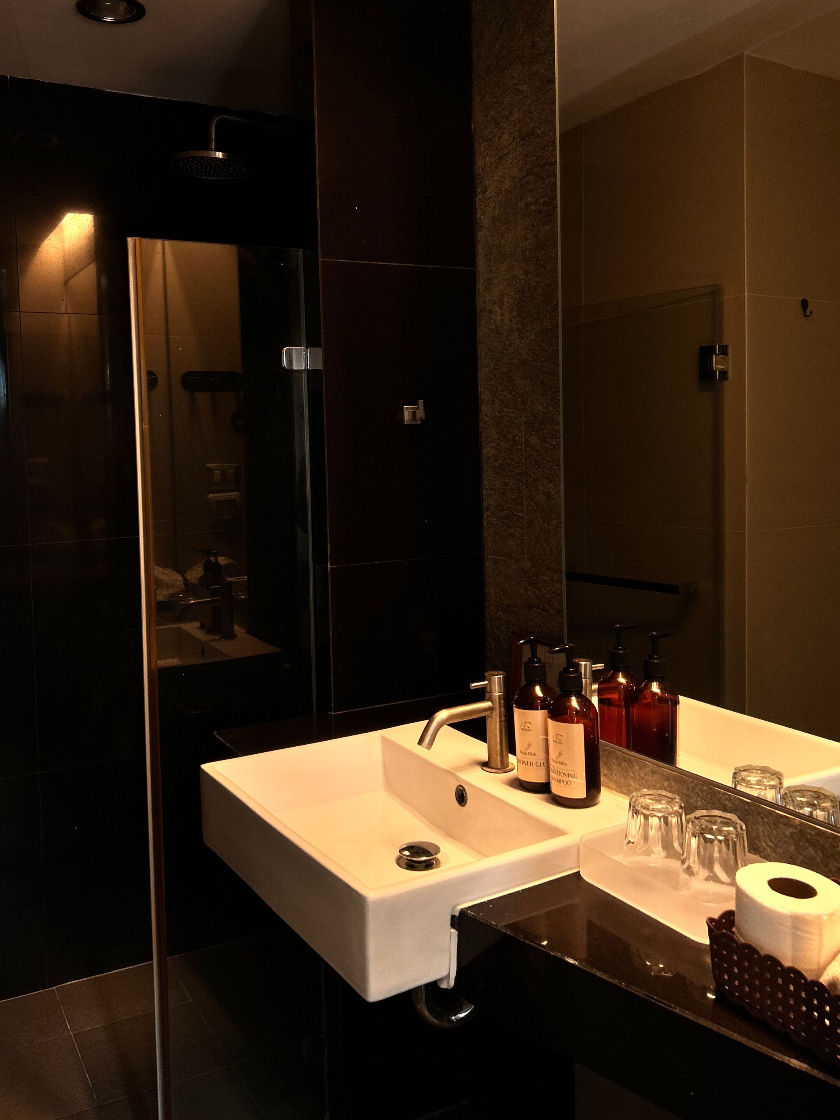 A modern bathroom with a large mirror, a white sink, and toiletries.