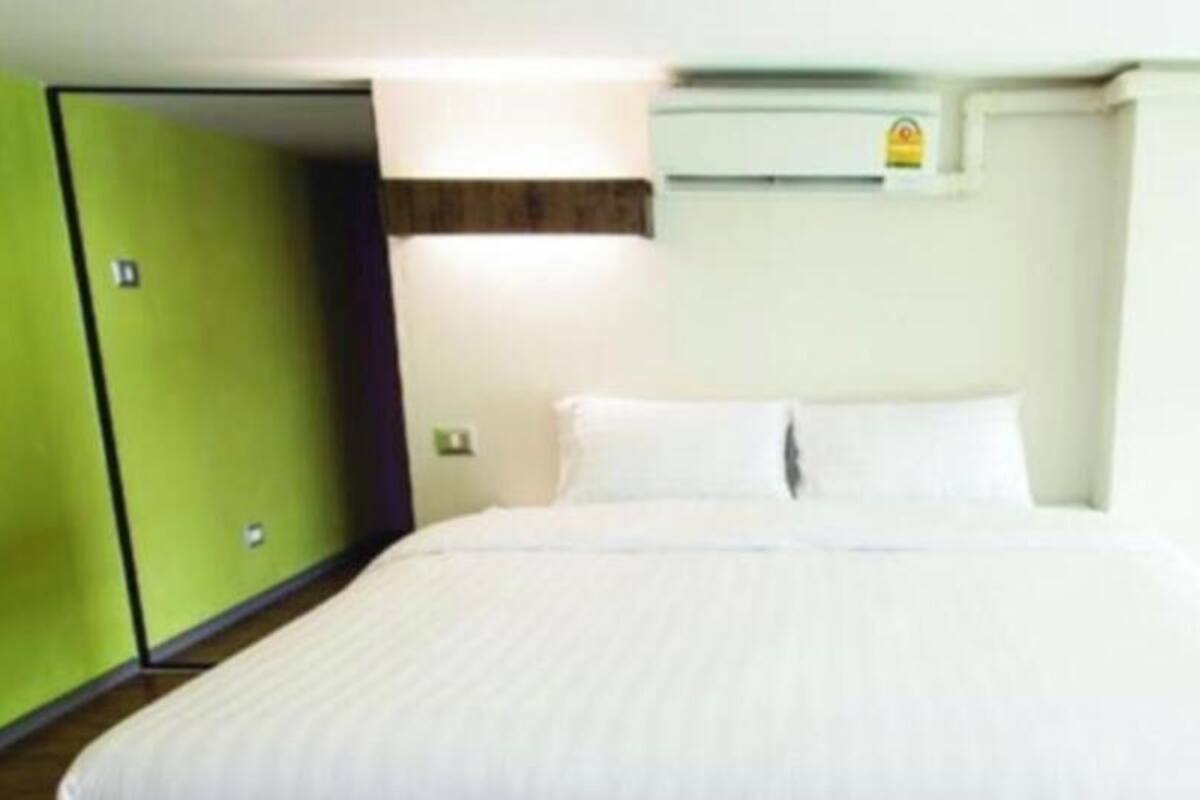 Una camera d'albergo con un letto, un armadio verde e una finestra.