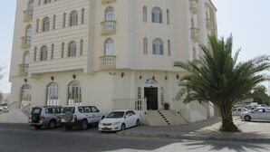A multi-story building with a symmetrical facade, multiple balconies, and a central entrance with steps. - Alferdous Hotel Apartments (Muscat)