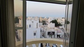 A view from a balcony with a railing, overlooking a cityscape with buildings and parked cars. - Alferdous Hotel Apartments (Muscat)