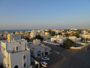 A coastal town with white buildings, a clear sky, and a view of the sea. - Alferdous Hotel Apartments (Muscat)