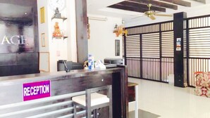 A reception area with a reception desk, a clock, and a decorative wall with vertical lines. - The Bird Cage Patong Guesthouse (Kathu)