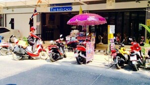 A street scene with parked motorcycles and a shop named "The Bird Cage". - The Bird Cage Patong Guesthouse (Kathu)