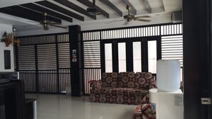 A modern living room with a sofa, ceiling fans, and a large window with blinds. - The Bird Cage Patong Guesthouse (Kathu)