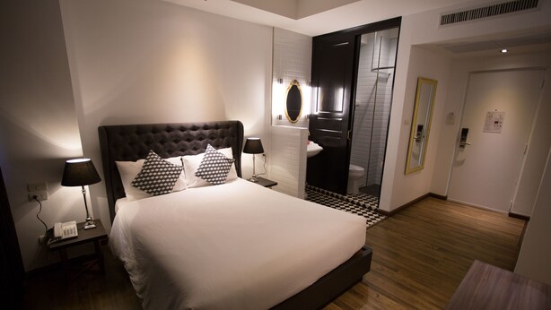 Habitación de hotel moderna con una cama grande, lámparas de noche, un espejo y suelo de madera.