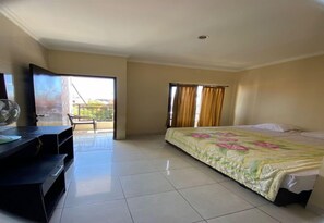 A hotel room with a bed, a desk, a chair, and a balcony. - Hotel Ayu Beach Inn (Kuta)