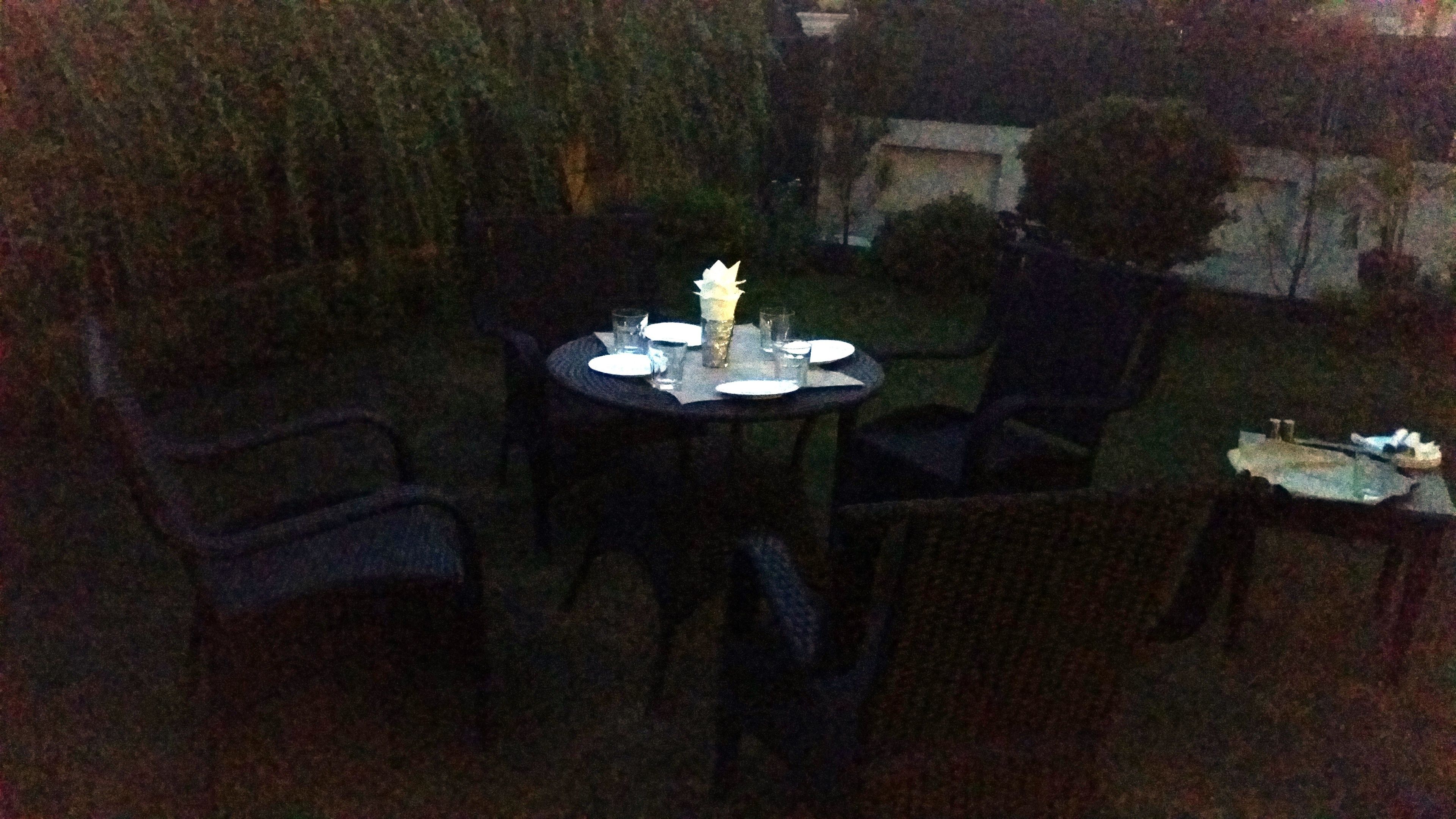 Un espace de restauration en plein air avec une table ronde pour quatre personnes, entourée de chaises.