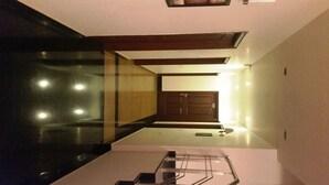 A modern interior with a glass partition, a wooden door, and a metal railing. - Tavisha Villa (Gurugram)