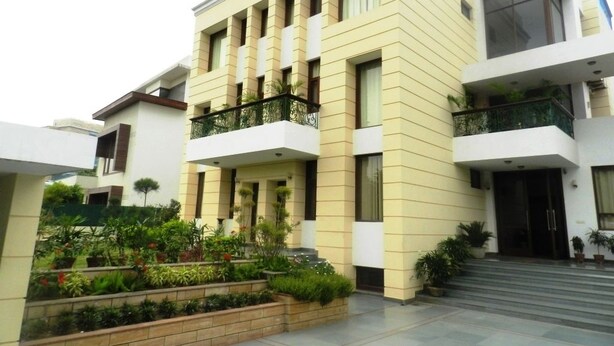 A modern building with a flat roof, multiple balconies, and a well-maintained garden area. - Tavisha Villa (Gurugram)