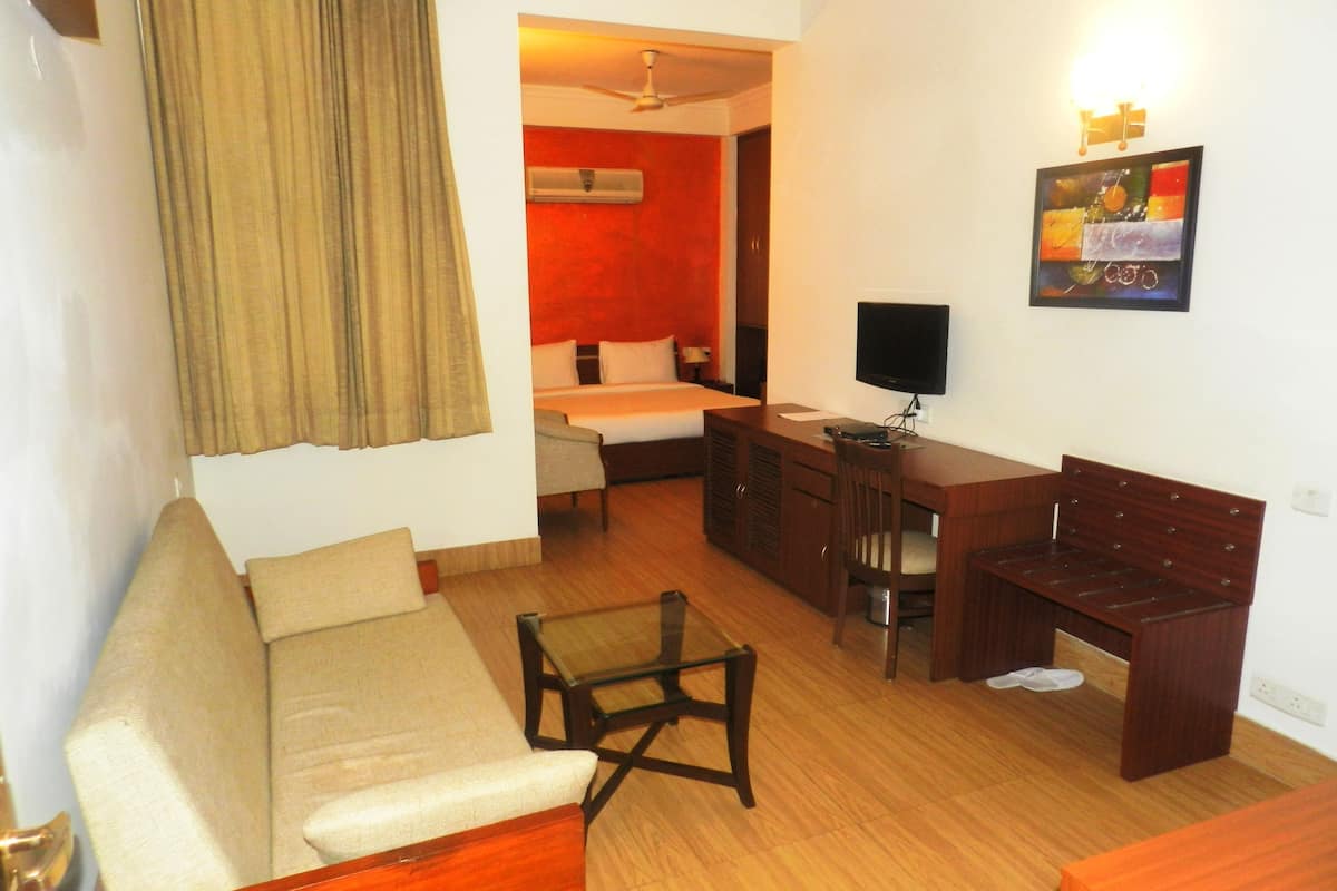 Una habitación de hotel con cama, escritorio, silla, sofá y televisor.