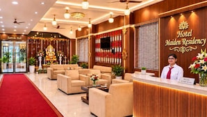 A hotel reception area with a red carpet, sofas, a reception desk, and a wall with a sign reading 'Hotel Maiden Residency'. - Hotel Maiden Residency (Ghaziabad)