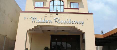 A hotel entrance with a sign reading "Maiden Residency."