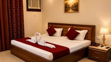 Habitación de hotel con una cama grande, una mesita de noche con lámpara, un cuadro en la pared y una ventana con aire acondicionado.