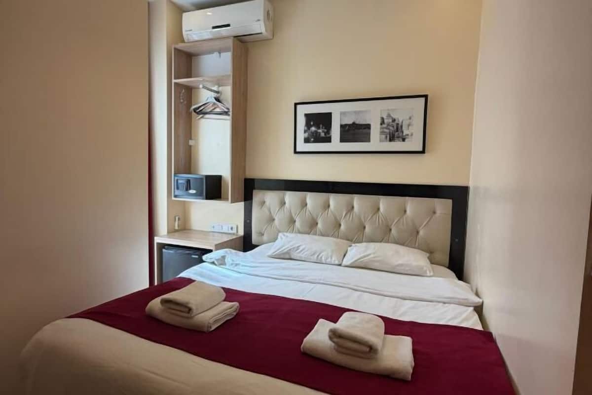 Ein Hotelzimmer mit Bett, Nachttisch, Spiegel und einem gerahmten Bild an der Wand.