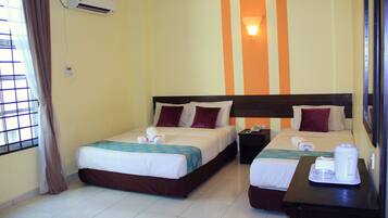 A hotel room with two beds, a nightstand, a coffee maker, and an air conditioning unit.