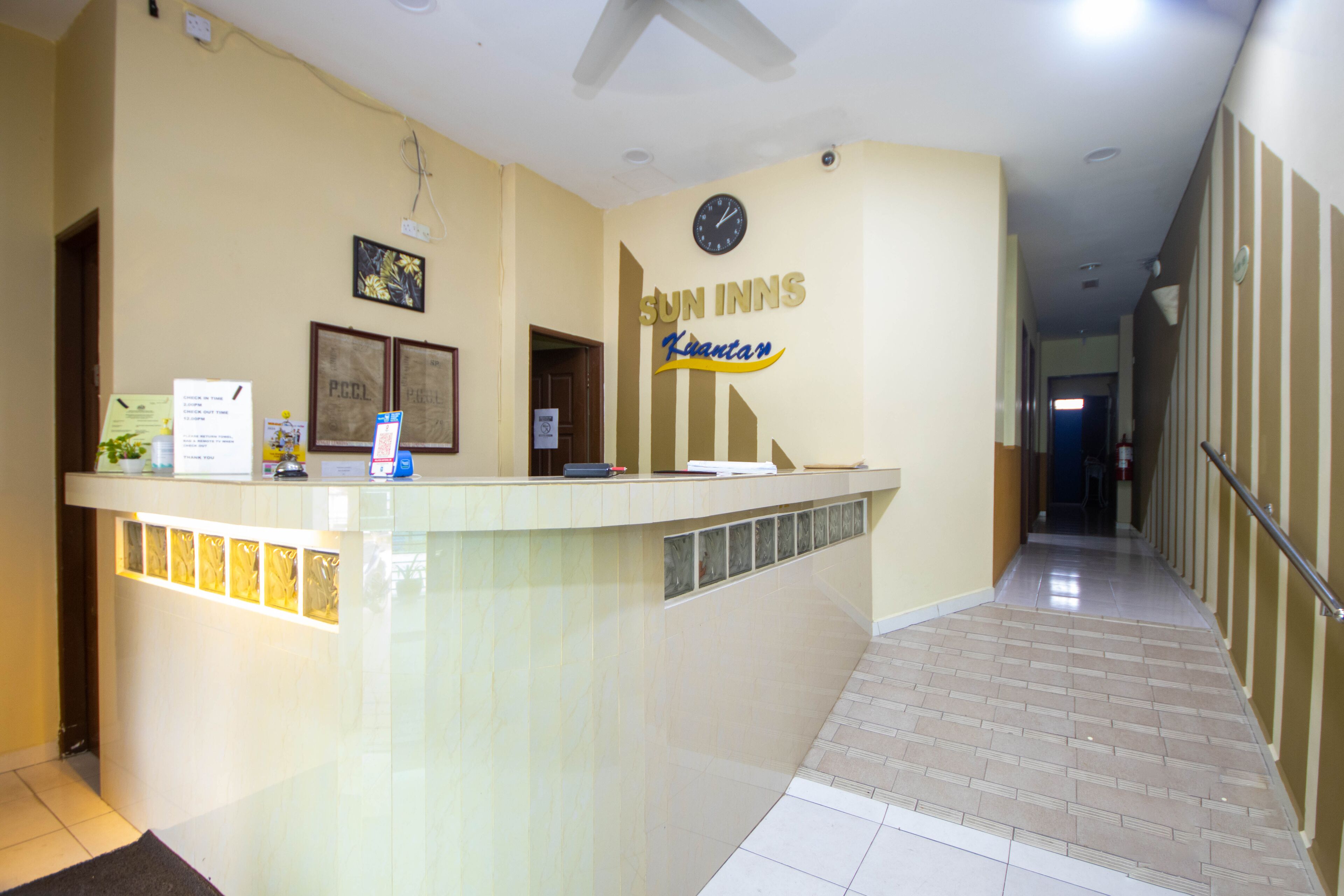 Ein Hotel-Rezeptionsbereich mit Empfangsschalter, einer Uhr und einem Schild mit der Aufschrift 'Sun Inns Kuantan'.