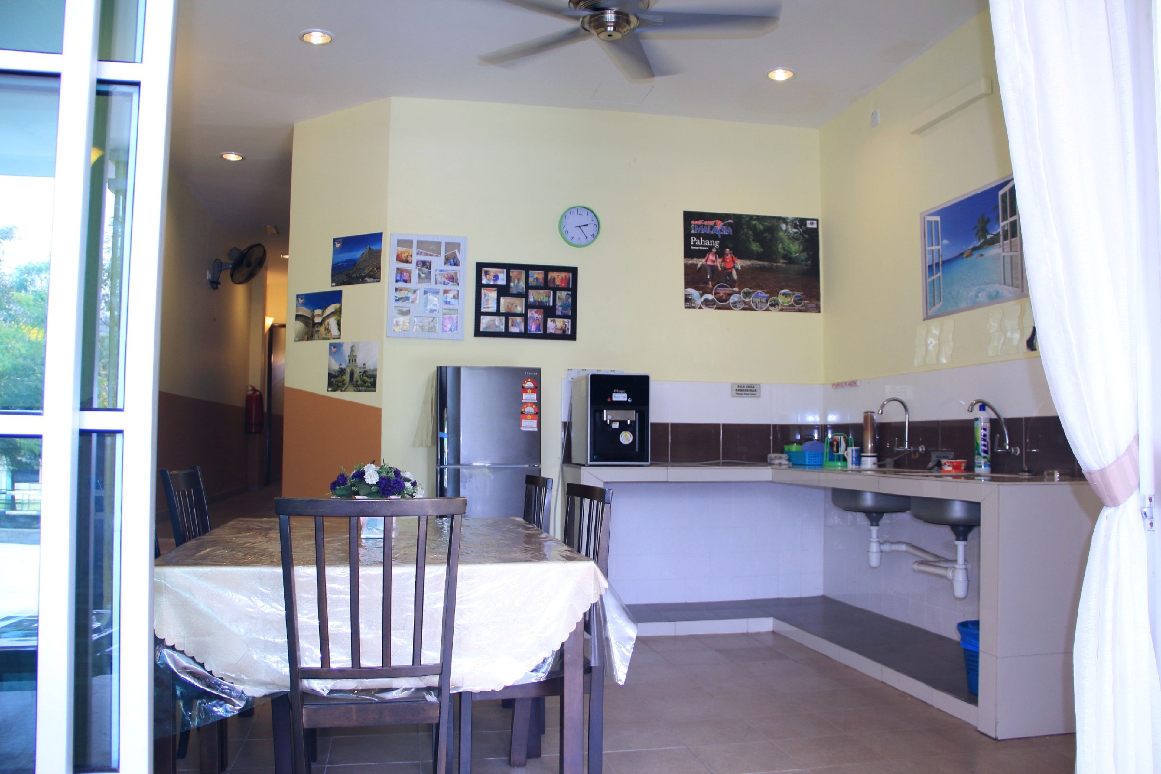 Cocina compacta con comedor, refrigerador, un reloj y ventana con vistas.