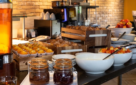 Un bufé con distintos alimentos, como muffins, frutas y salsas.