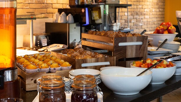 Een buffet met diverse gerechten, waaronder muffins, fruit en sausjes.