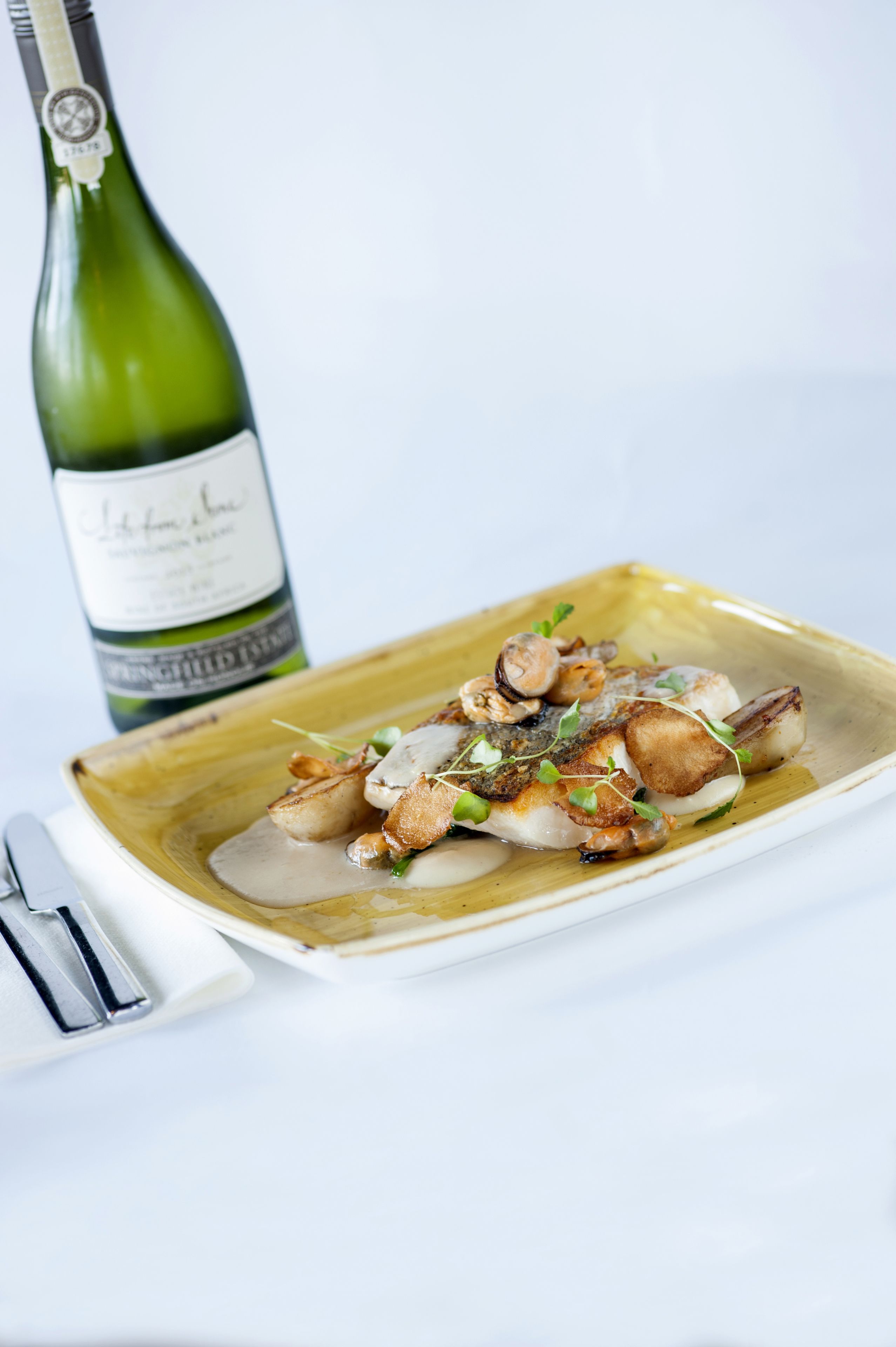 Un plato de comida con champiñones y una botella de vino.